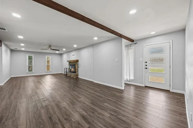 a view of empty room with wooden floor and kitchen