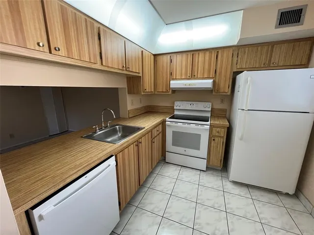 a kitchen with a stove top oven a sink and a refrigerator