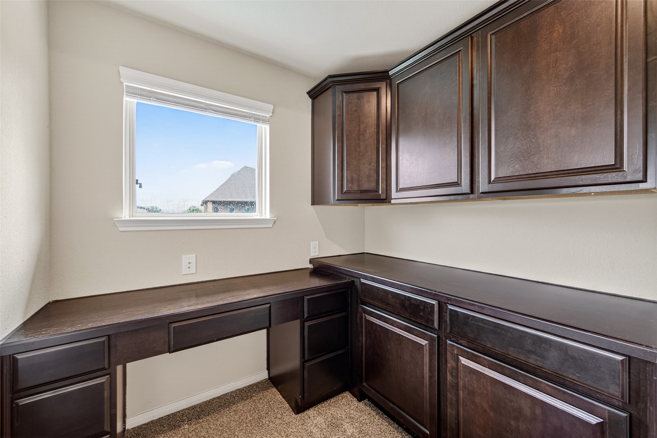 25611 Ellis Ridge Court Katy, TX 77494 - Photo 26 of 49 This photo showcases a compact home office or study area with rich dark wood cabinetry and desk space, featuring a window that provides natural light and a view outside.