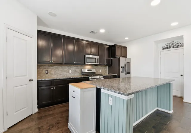 a kitchen with stainless steel appliances granite countertop a sink stove and refrigerator