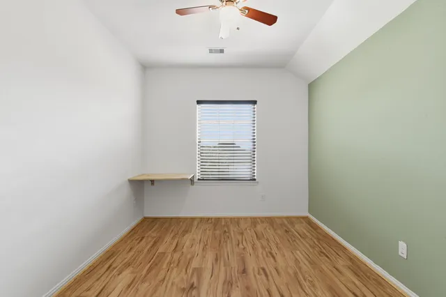 an empty room with a hardwood and ceiling fan