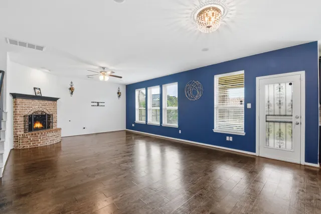 a view of an empty room with wooden floor and a fireplace