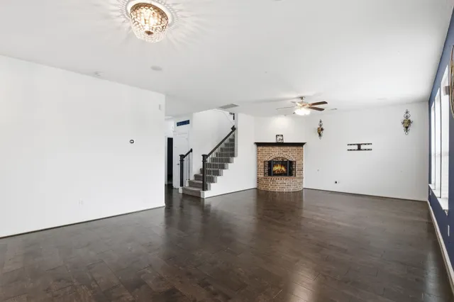 an empty room with wooden floor fireplace and windows