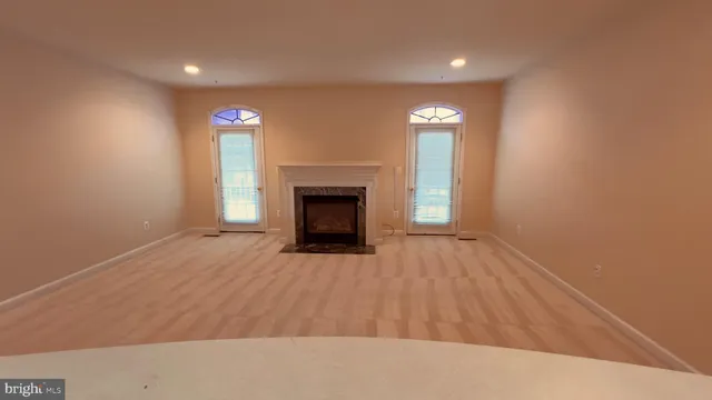 a view of an empty room with wooden floor fireplace and a window