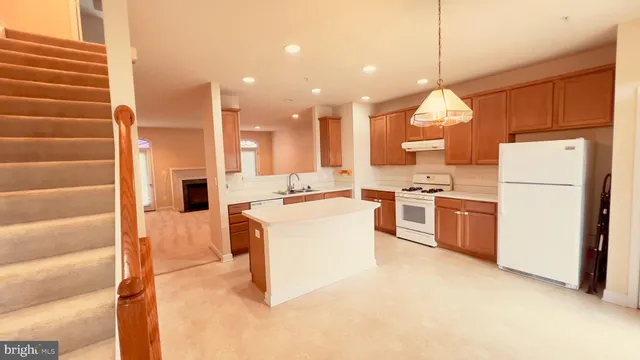 a kitchen with kitchen island a white counter top space a sink and a refrigerator