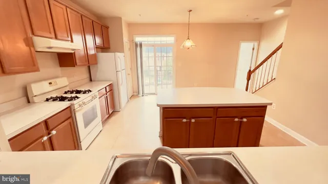 a kitchen with stainless steel appliances a stove a sink and a refrigerator with wooden floor