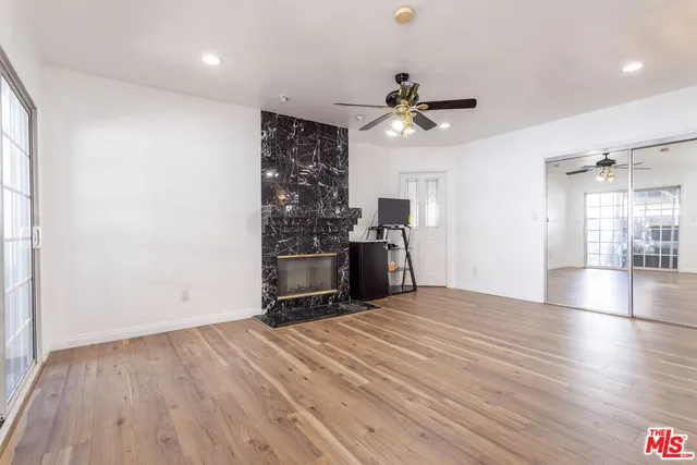 an empty room with wooden floor ceiling fan and windows