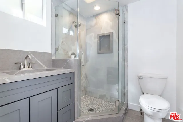 a bathroom with a granite countertop sink toilet and shower