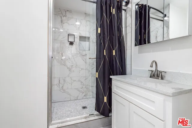 a bathroom with a granite countertop sink a mirror and shower