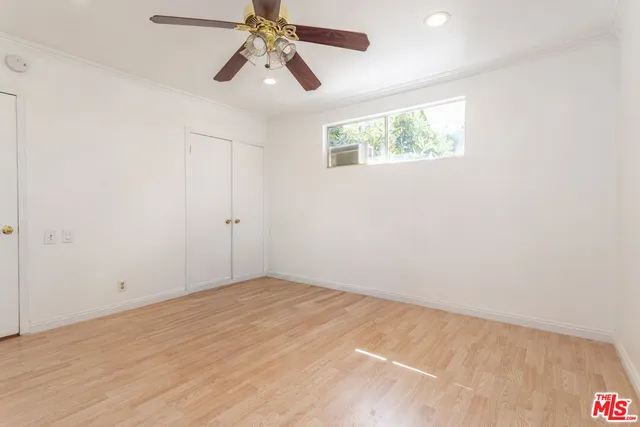 an empty room with windows and fan