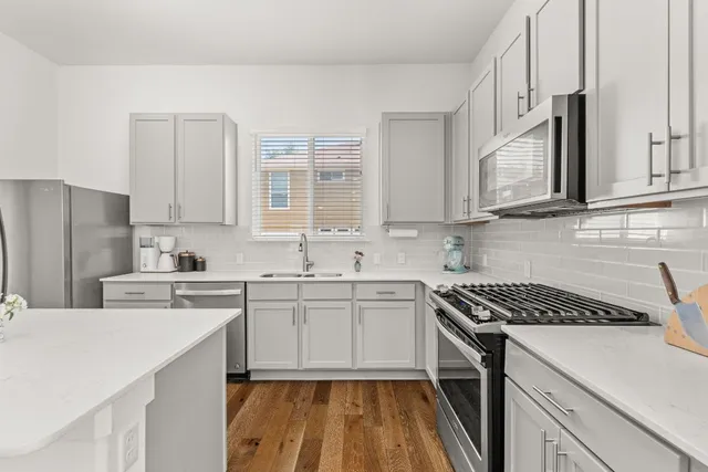 a kitchen with stainless steel appliances granite countertop a sink stove refrigerator and cabinets