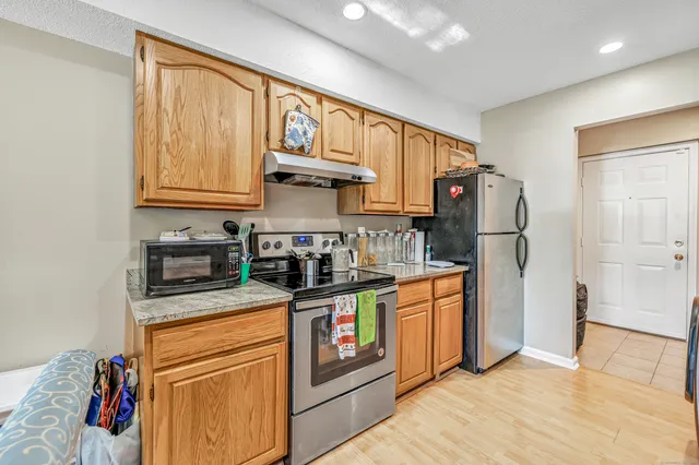 a kitchen with stainless steel appliances granite countertop a refrigerator a stove and a sink