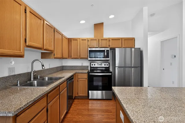 a kitchen with stainless steel appliances granite countertop a sink refrigerator and microwave