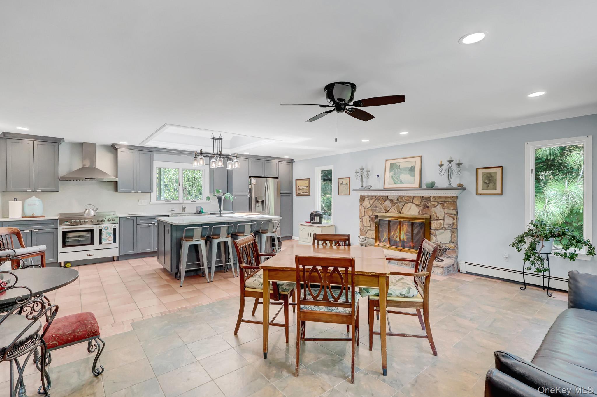 100 Elwood Road Northport, NY 11768 - Photo 4 of 39 Open-concept living area featuring a stone fireplace with wood mantel, tile flooring, and multiple windows