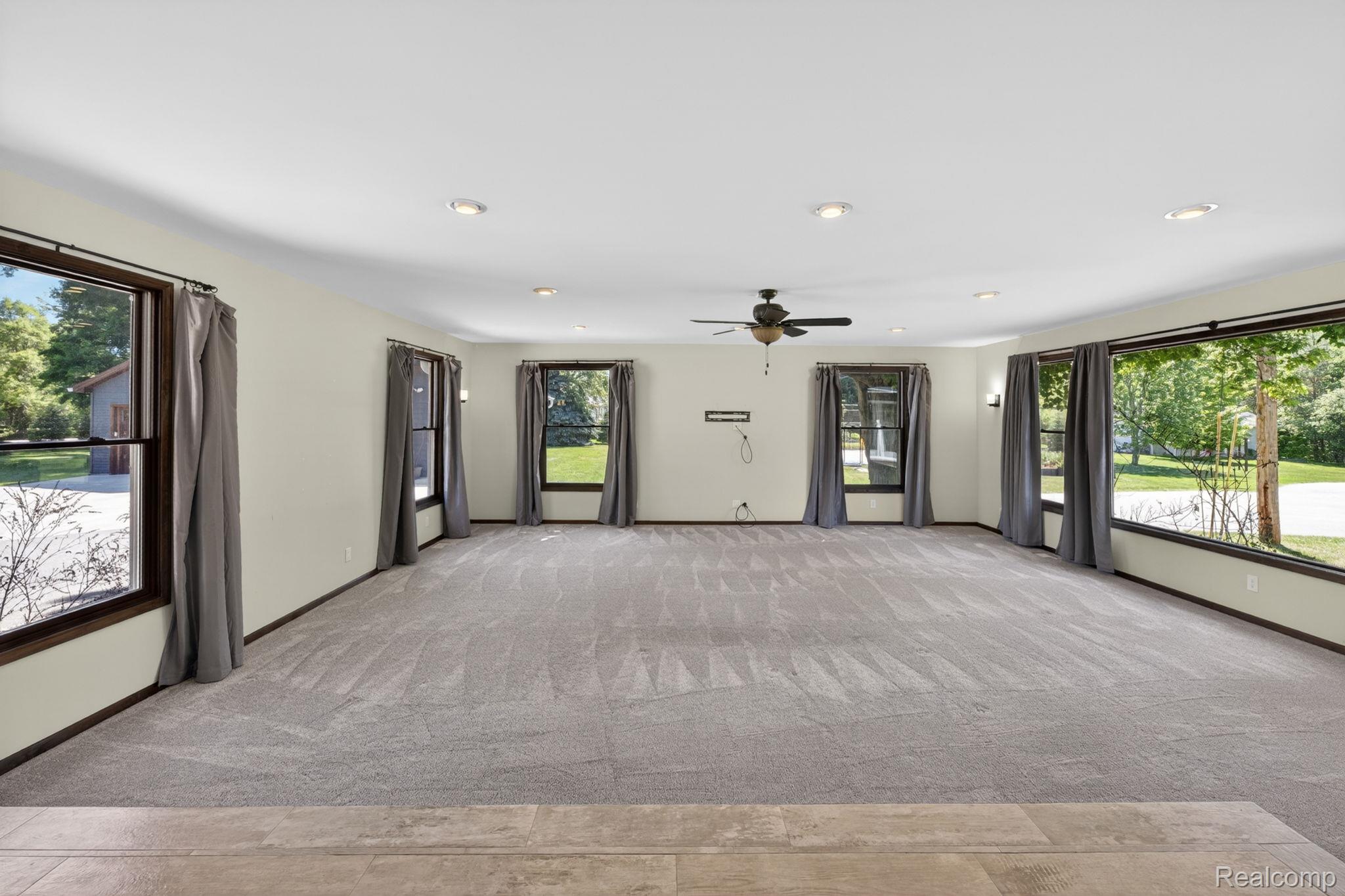 9353 Hill Road Swartz Creek, MI 48473 - Photo 16 of 98 Spacious room featuring light gray carpeting, multiple windows with dark trim, recessed lighting, and a ceiling fan
