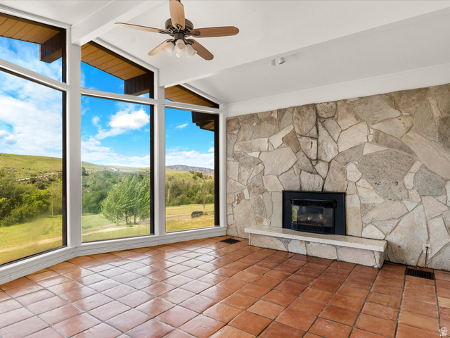 15680 North Beaver Dam Road Collinston, UT 84306 - Photo 6 of 49 Room featuring a full wall of floor-to-ceiling windows, a stone-clad fireplace with hearth, terracotta tile flooring, and a ceiling fan