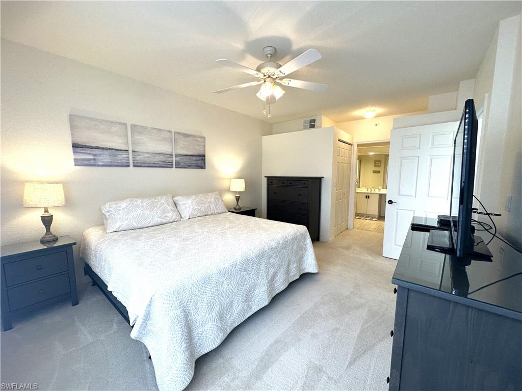 6816 Satinleaf Road South, Unit 102 Naples, FL 34109 - Photo 15 of 35 a bedroom with a large bed and a chandelier