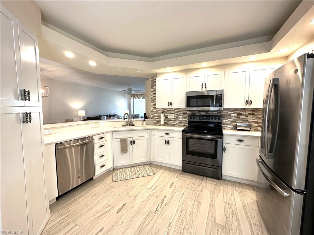 6816 Satinleaf Road South, Unit 102 Naples, FL 34109 - Photo 5 of 35 a kitchen with white cabinets stainless steel appliances and sink