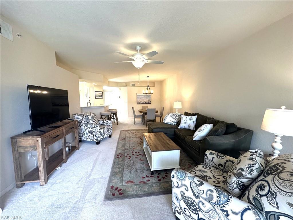 6816 Satinleaf Road South, Unit 102 Naples, FL 34109 - Photo 8 of 35 a living room with furniture and a flat screen tv