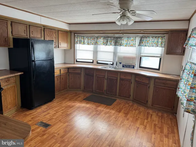 a kitchen with stainless steel appliances granite countertop a refrigerator a sink dishwasher a stove and white countertops with wooden floor