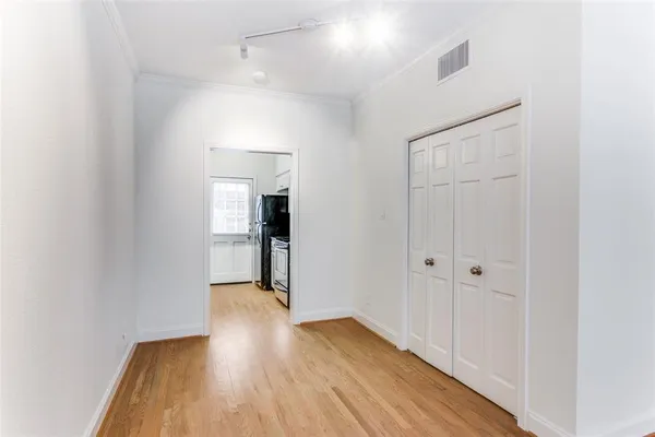 a view of a hallway with wooden floor and a bathroom