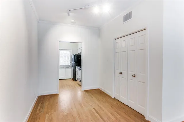 a view of a hallway with wooden floor and a bathroom