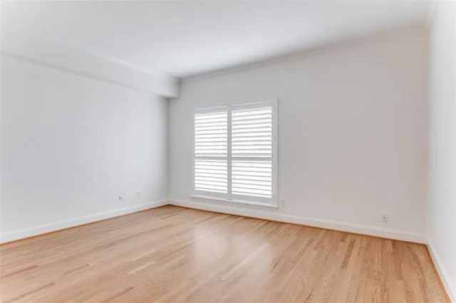 an empty room with wooden floor and window