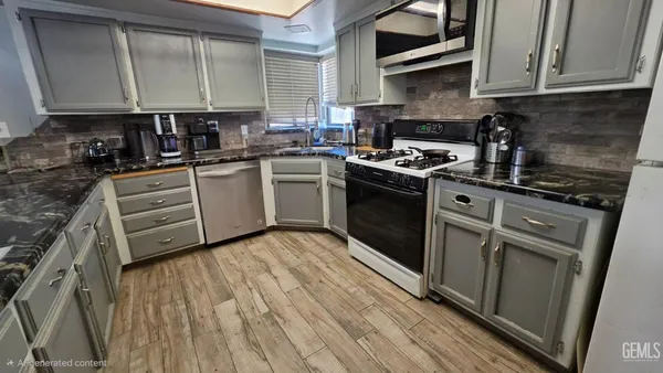 a kitchen with granite countertop a stove a sink a refrigerator and cabinets