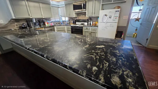 a kitchen with stainless steel appliances granite countertop a refrigerator a stove and a sink with wooden floor