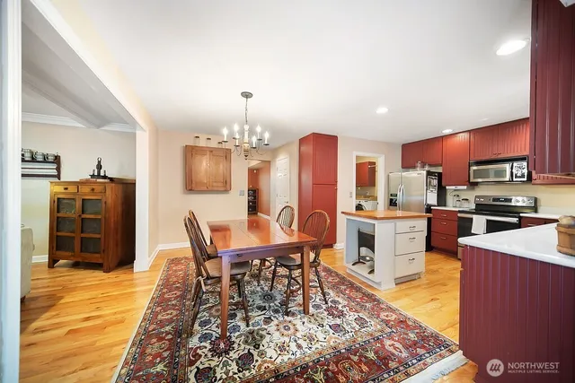 a kitchen with stainless steel appliances wooden floor dining table and chairs