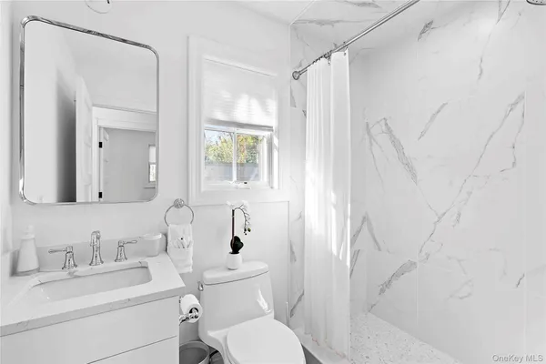 a bathroom with a toilet sink vanity and mirror
