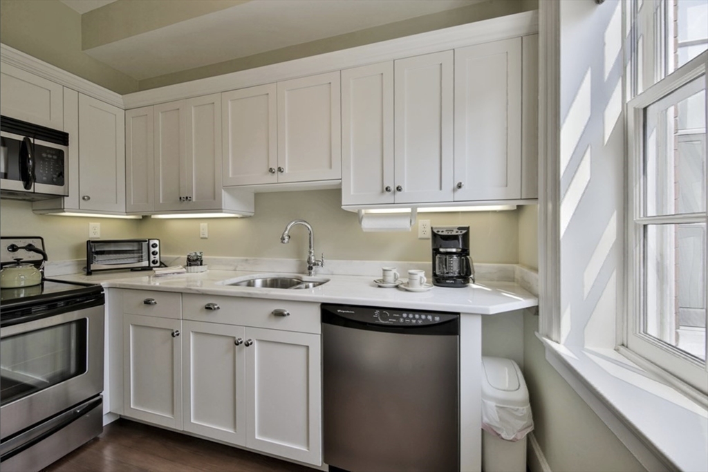 26 Winter Street Salem, MA 01970 - Photo 30 of 42 a kitchen with stainless steel appliances granite countertop a sink and dishwasher a stove top oven with white cabinets