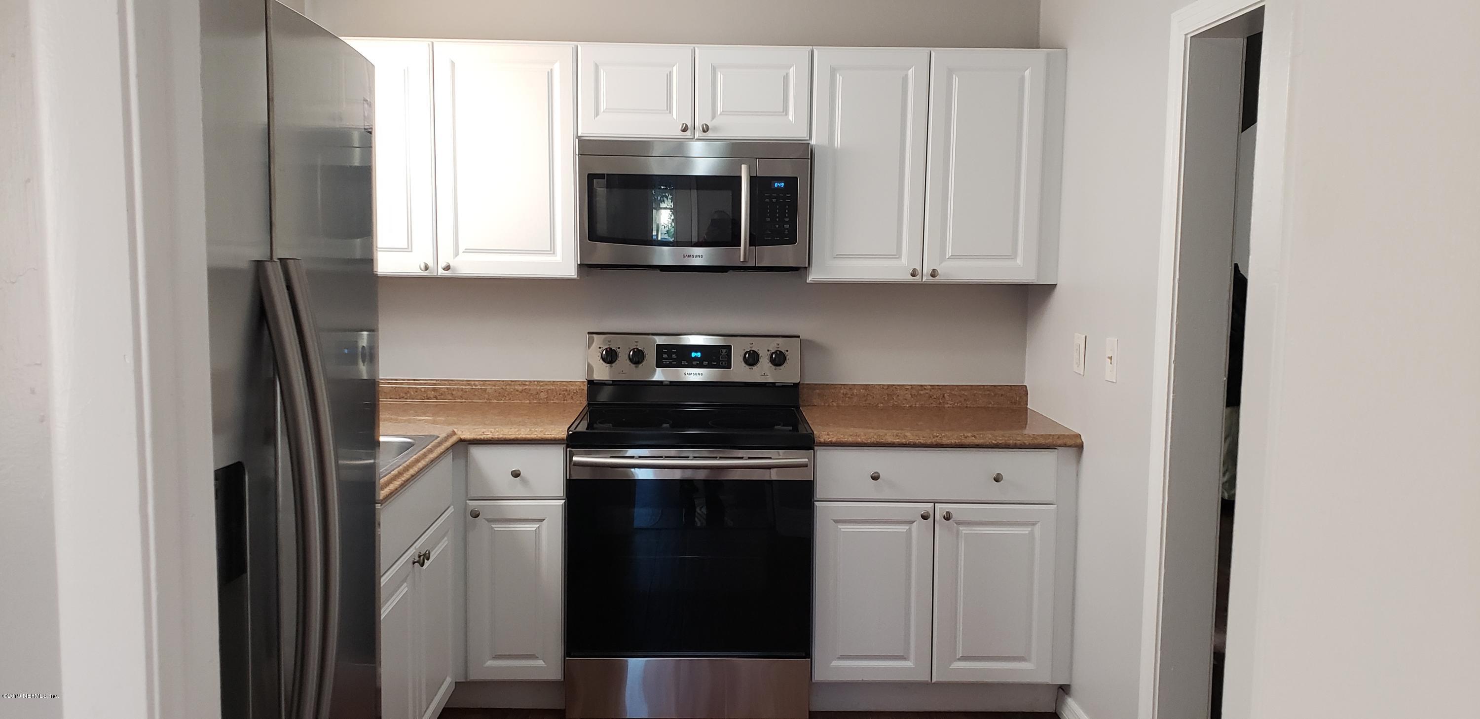 4633 Manchester Road Jacksonville, FL 32210 - Photo 13 of 26 a kitchen with stainless steel appliances granite countertop white cabinets a stove a microwave and a refrigerator