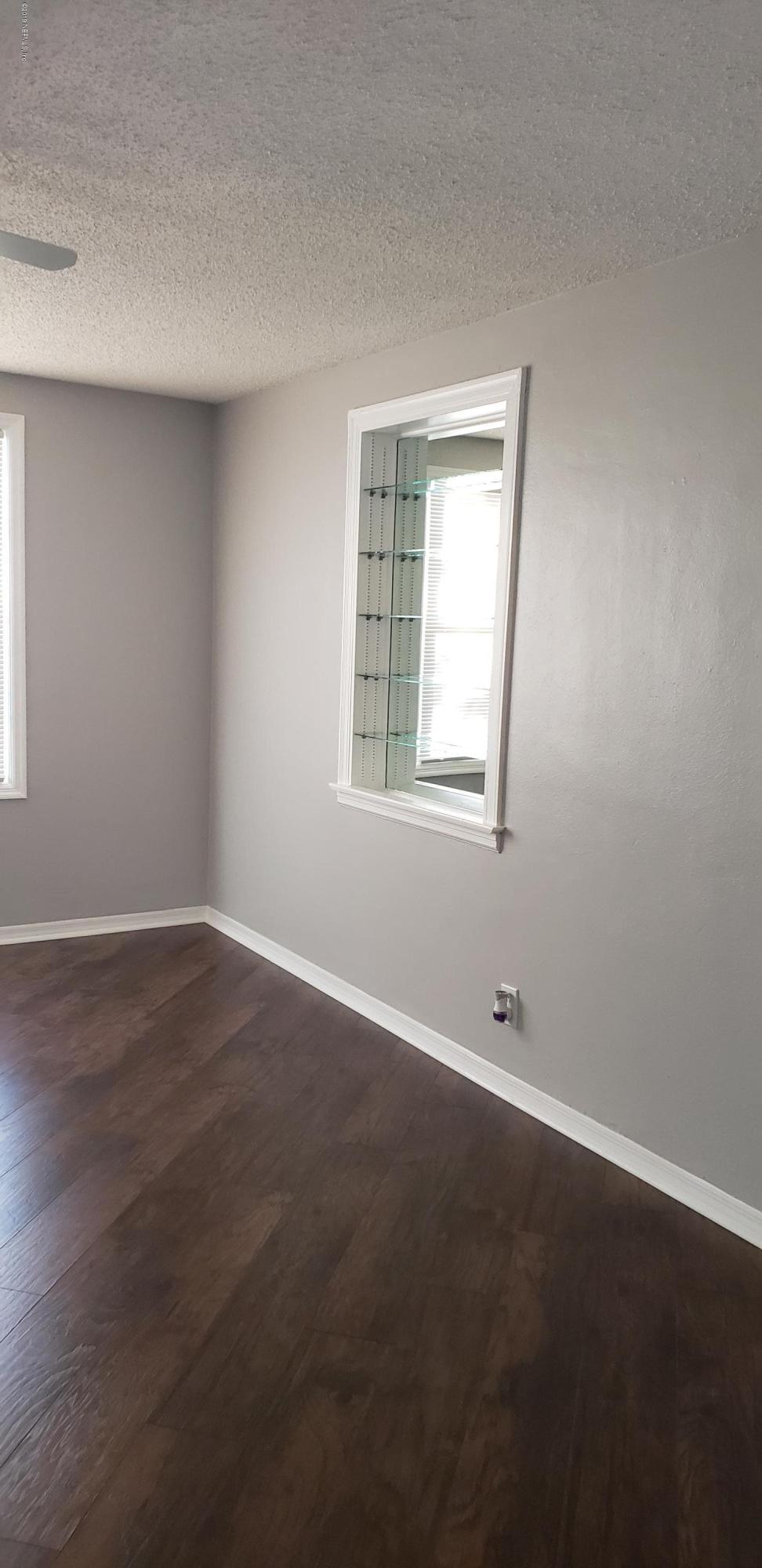 4633 Manchester Road Jacksonville, FL 32210 - Photo 24 of 26 an empty room with wooden floor and windows