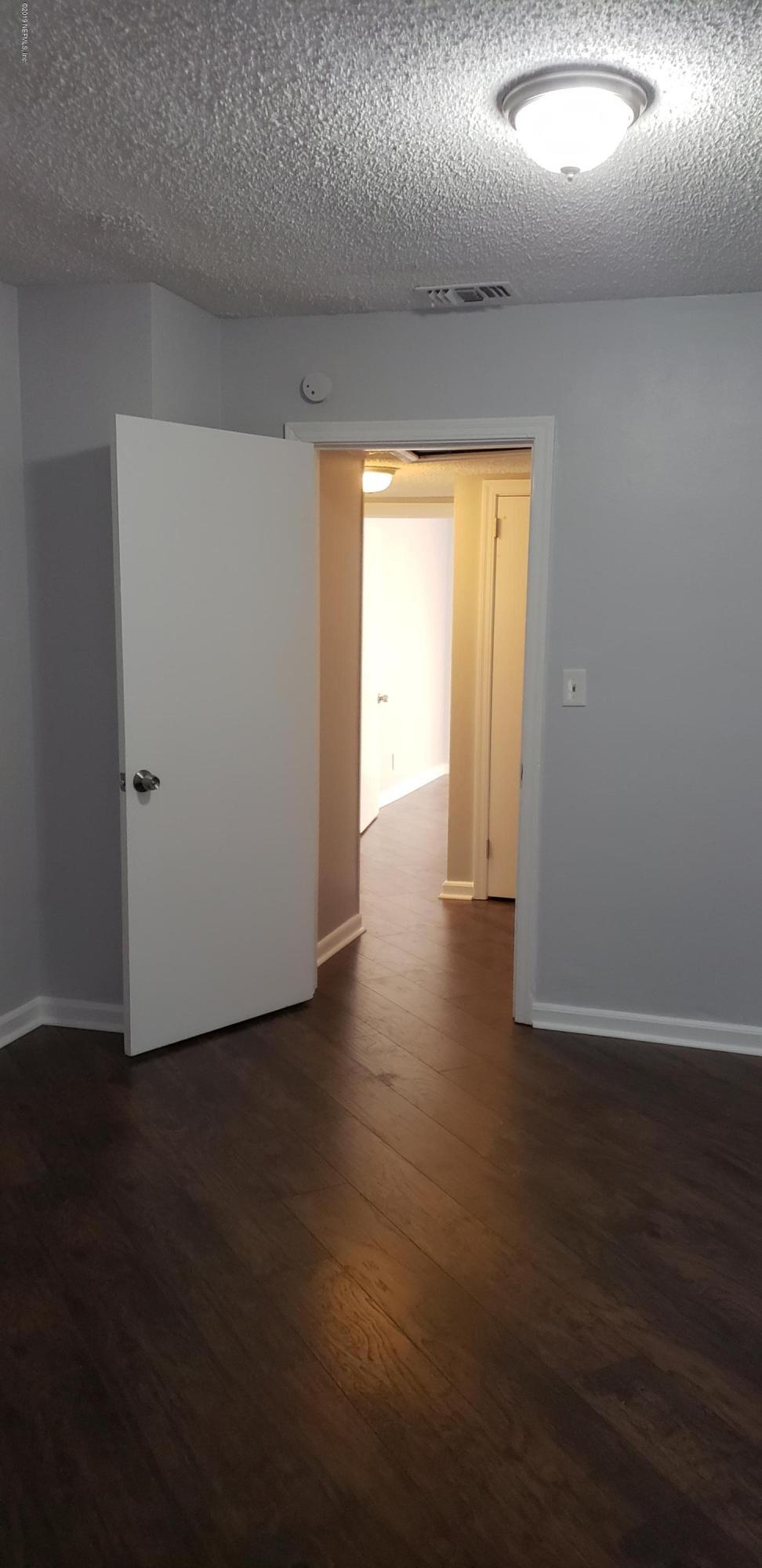 4633 Manchester Road Jacksonville, FL 32210 - Photo 5 of 26 an empty room with wooden floor and windows with curtains
