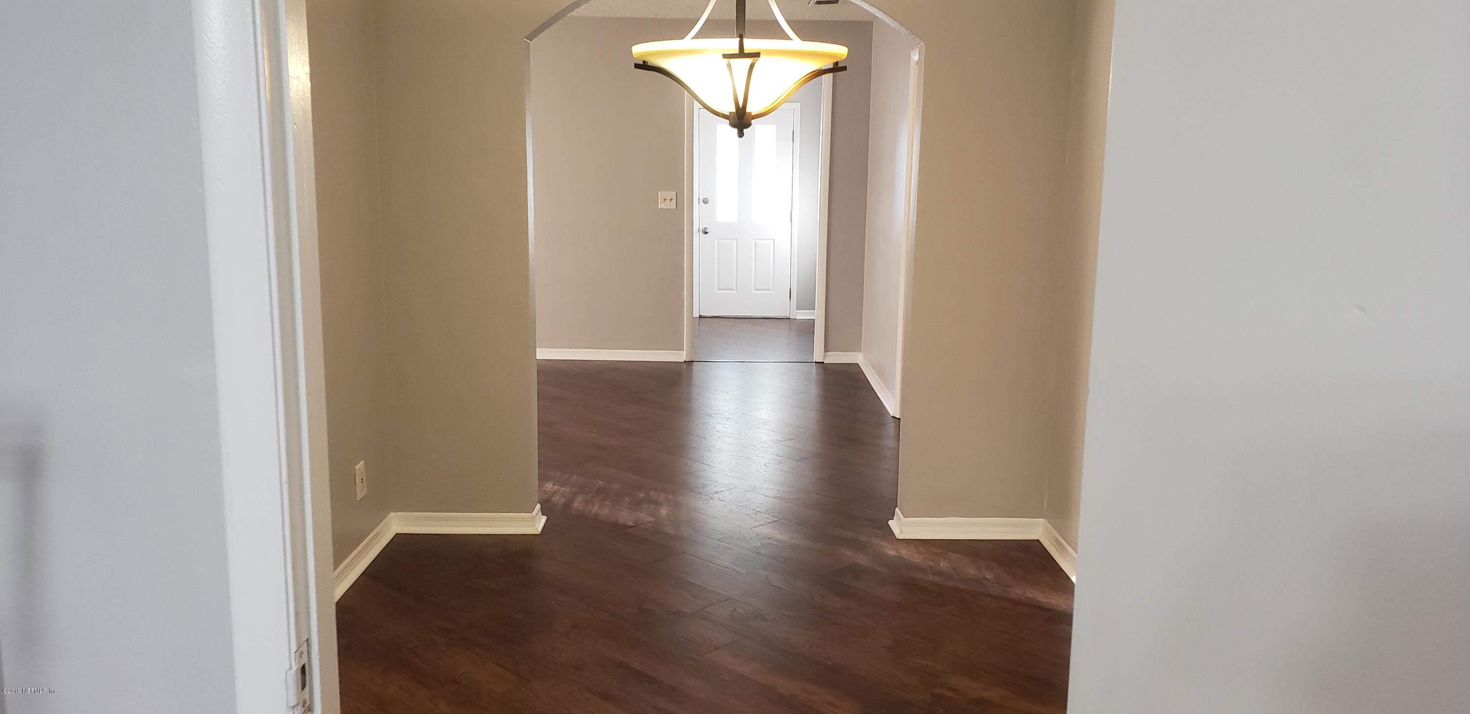 4633 Manchester Road Jacksonville, FL 32210 - Photo 9 of 26 a view of a hallway with wooden floor and a chandelier