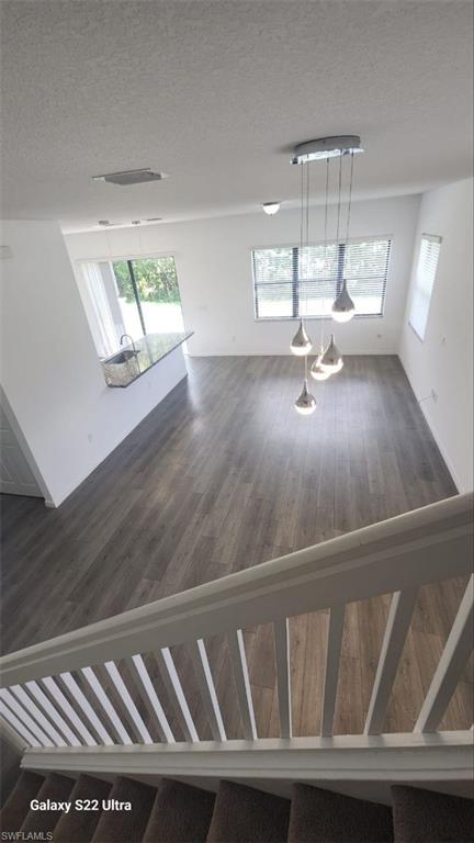 9015 Madrid Circle Naples, FL 34104 - Photo 13 of 15 Stairway featuring wood finished floors, a wealth of natural light, and a textured ceiling