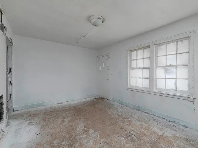 an empty room with fireplace and windows