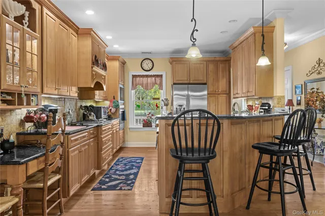 a kitchen with stainless steel appliances granite countertop a stove top oven a sink a dining table and chairs with wooden floor