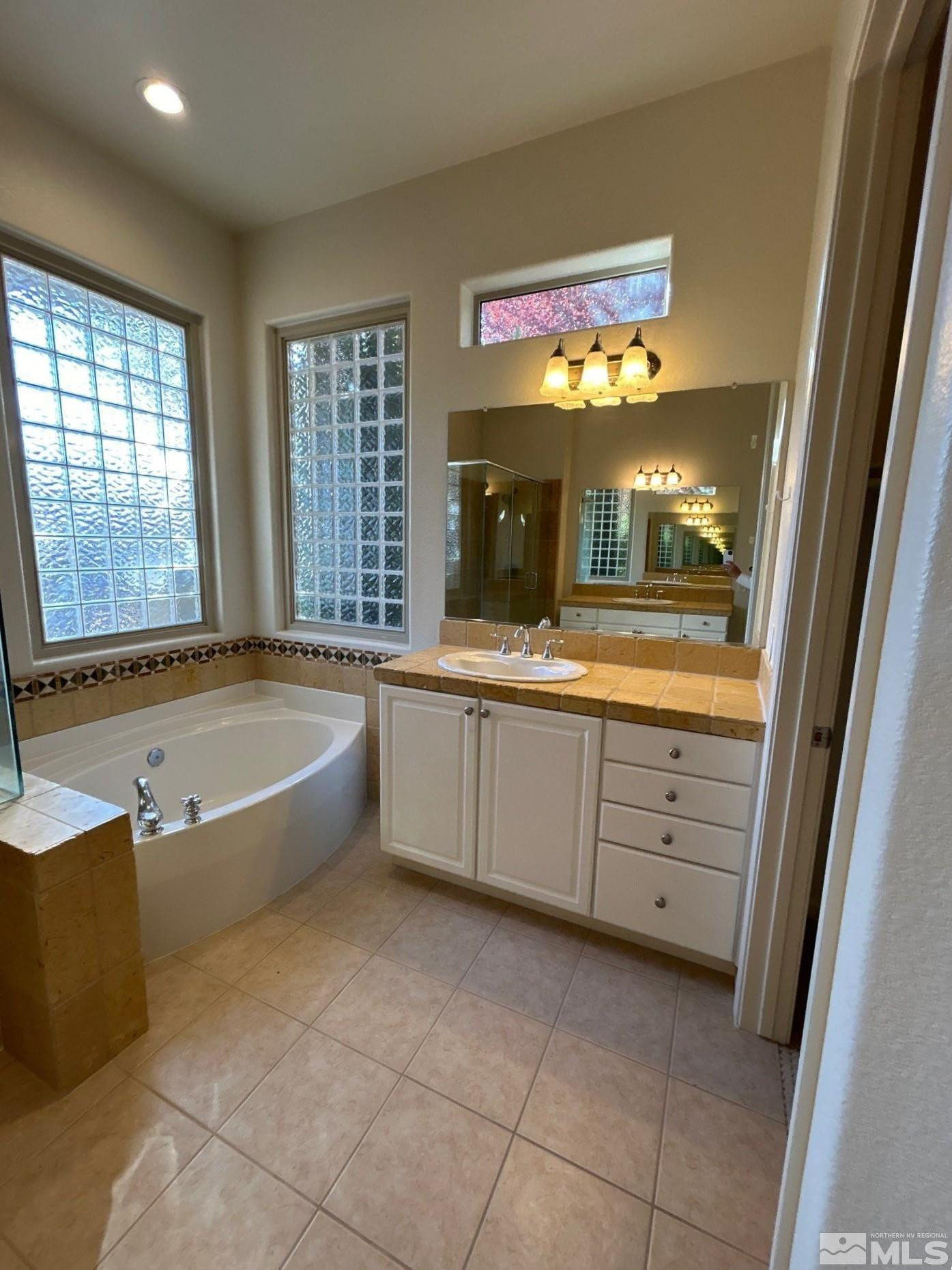9900 Wilbur May Parkway, Unit 3402 Reno, NV 89521 - Photo 12 of 26 a bathroom with a bathtub a sink and a large mirror