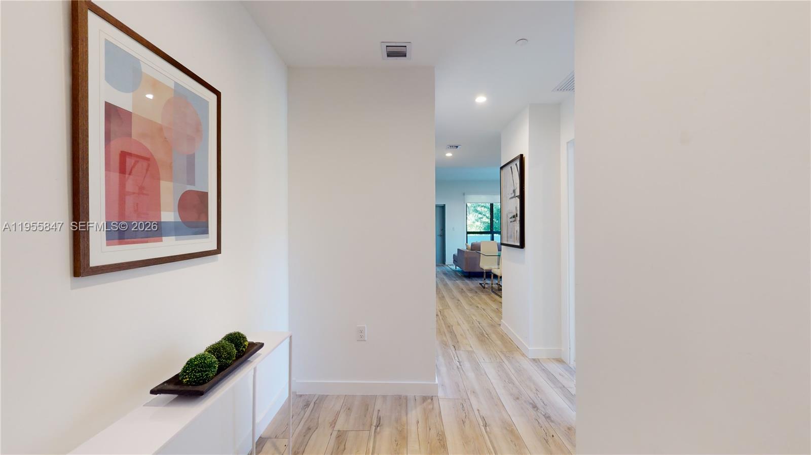 24705 Southwest 129th Avenue, Unit 107 Homestead, FL 33032 - Photo 2 of 33 a view of a hallway with wooden floor and a potted plant