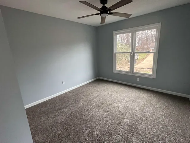 an empty room with a window and a fan