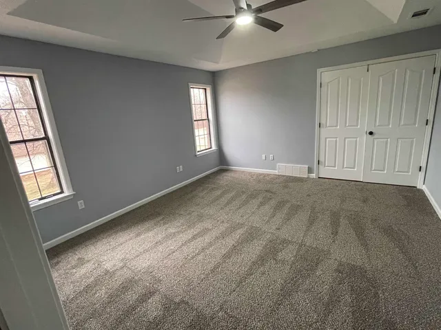 an empty room with windows and fan