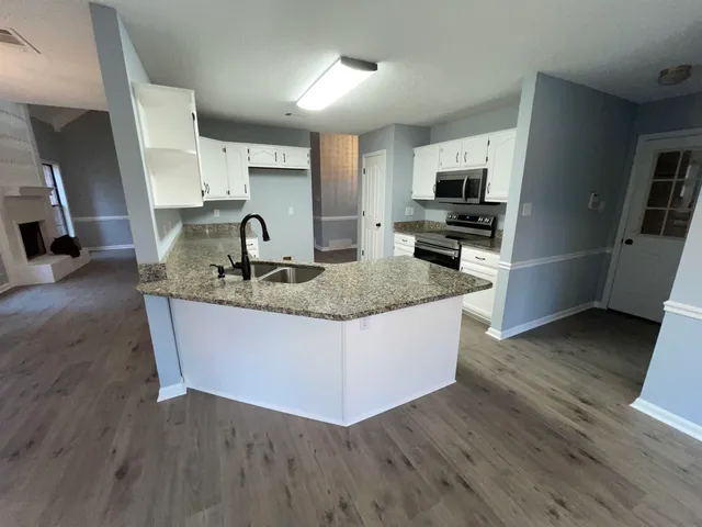 a kitchen with kitchen island granite countertop a sink a counter top space and appliances