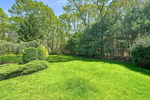a view of a house with a big yard and large trees