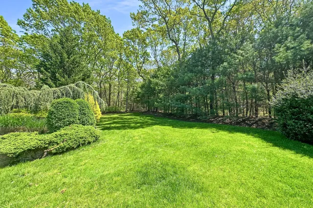 a view of a house with a big yard and large trees