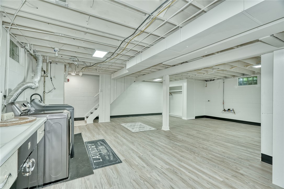 255 Fairport Road East Rochester, NY 14445 - Photo 21 of 26 An open and finished basement features wood-look flooring and integrated laundry hookups.