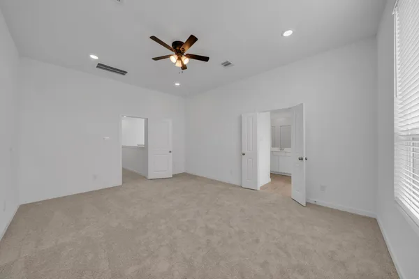 an empty room with chandelier fan and windows