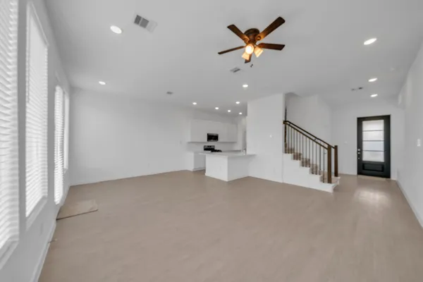 an empty room with chandelier fan and windows