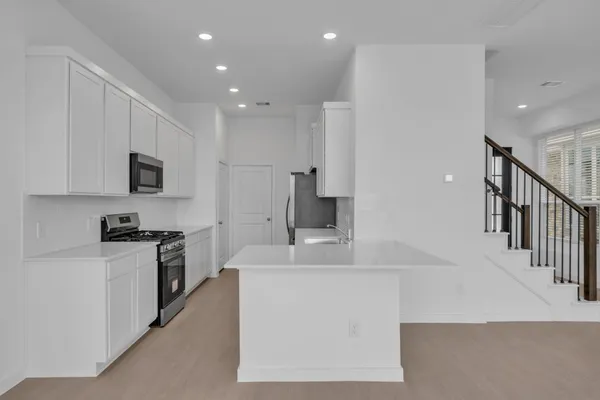 a large kitchen with stainless steel appliances a large counter top a stove and a sink